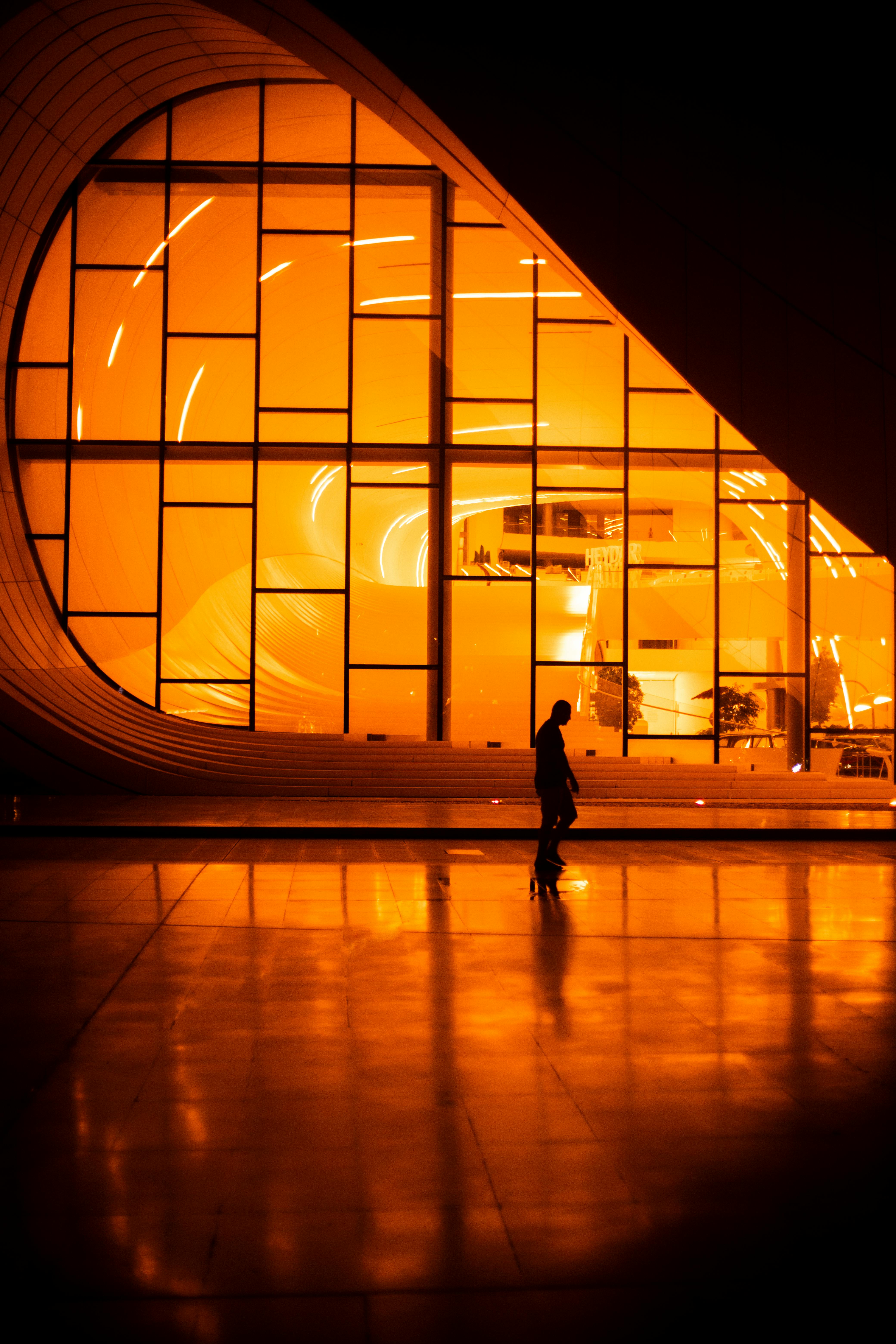 A silhouette stands before the illuminated Heydar Aliyev Centre in Baku, Azerbaijan.