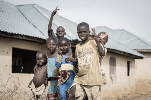 Free Group of children smiling and waving in a village in Nigeria, capturing friendship and joy. Stock Photo