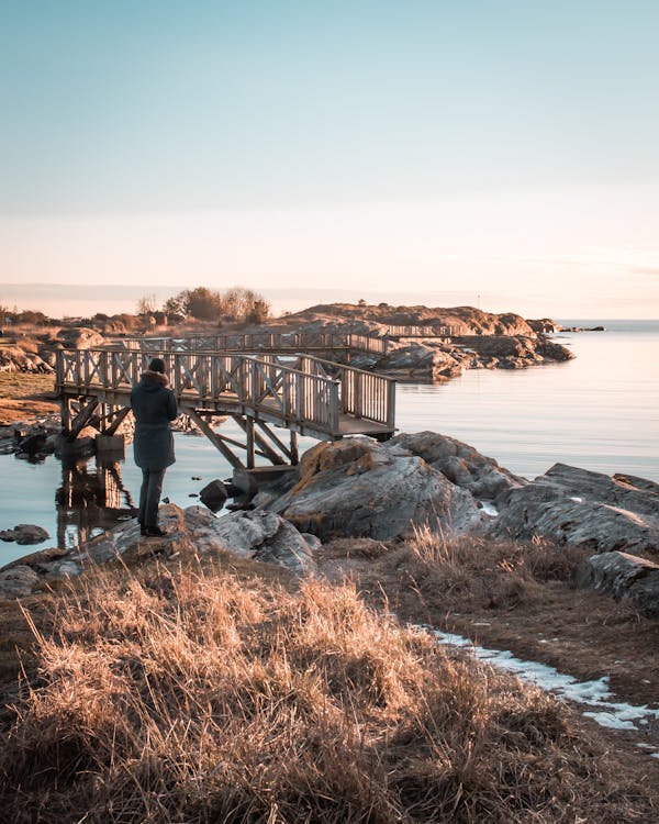 Person Standing in Front of Wooden Bridge