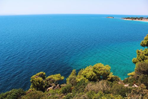 Free Captivating view of a vibrant blue sea and lush greenery along the coastline. Stock Photo
