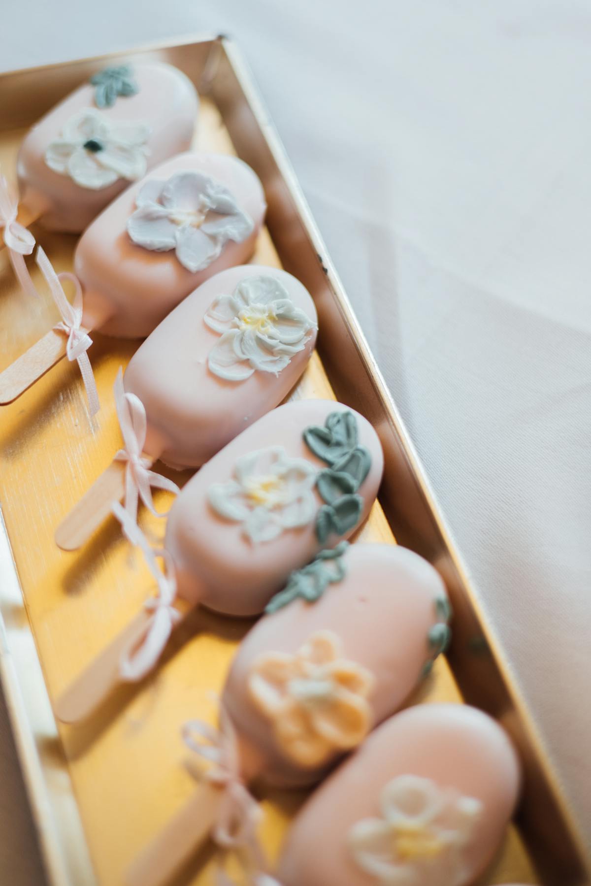 Cake pops with pink icing and sugar flowers arranged on a tray
