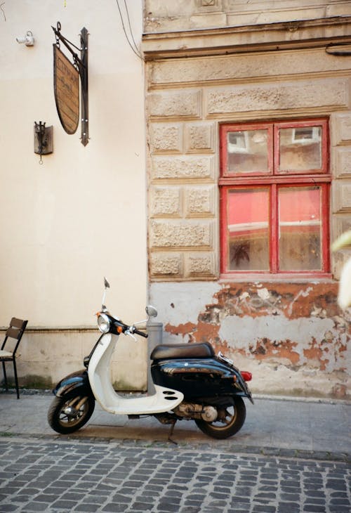 Black and White Vespa Parked Under the Restaurant Sign