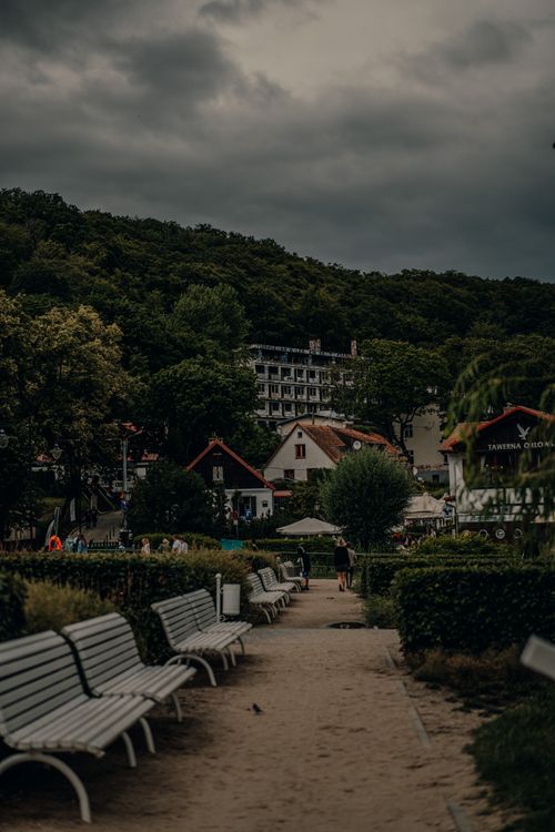 Free Peaceful park walkway in Gdynia Orlowo with benches and lush greenery under cloudy skies. Stock Photo