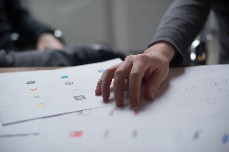 Hand prüft Logo-Entwürfe auf Papier – wann sich ein Rebranding für dein Unternehmen wirklich lohnt.