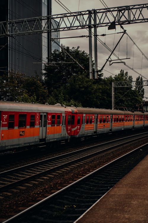 Free A vibrant urban train passing through a railway in Gdansk, Poland with office buildings nearby. Stock Photo