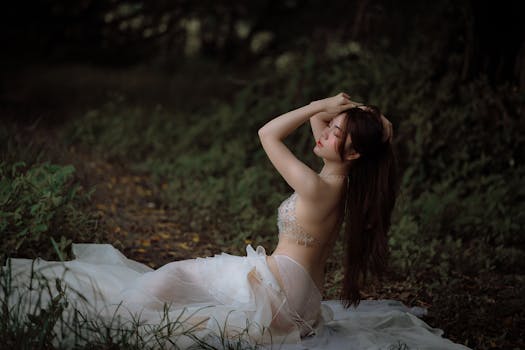 A young woman in elegant lingerie posing gracefully outdoors, surrounded by forest greenery.