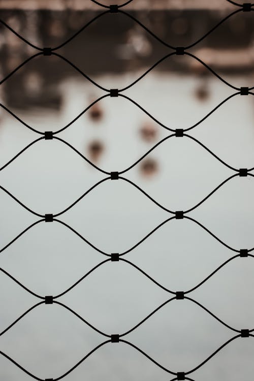 Water Seen Through Cells of Metal Mesh Fence
