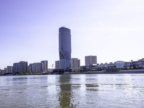 Free Stunning view of a modern skyscraper reflecting on the tranquil river in an urban cityscape. Stock Photo