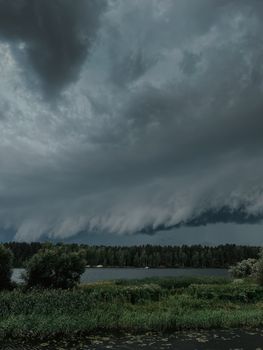 A dramatic storm front forms over a peaceful lake surrounded by lush greenery. Captured during twilight.