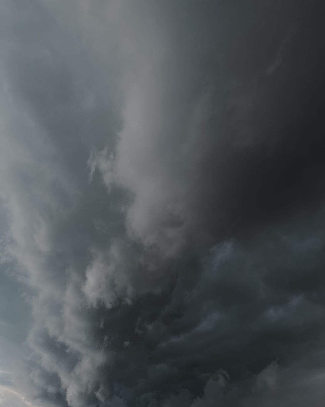 A dramatic vertical shot of dark storm clouds filling the sky, suggesting an impending storm.. dramatic, vertical, shot