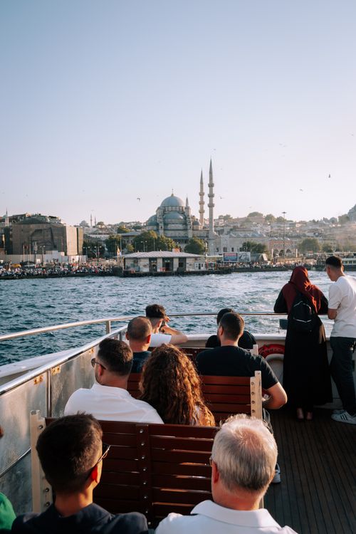 Free Passengers enjoy a scenic boat ride on the Bosphorus, Istanbul, with a mosque in the background. Stock Photo