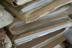 Close-up of old paper files stacked in vintage brown folders, organized and archived.