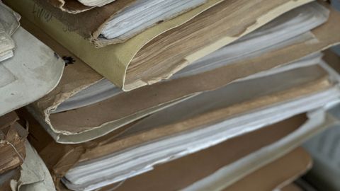 Close-up of old paper files stacked in vintage brown folders, organized and archived.