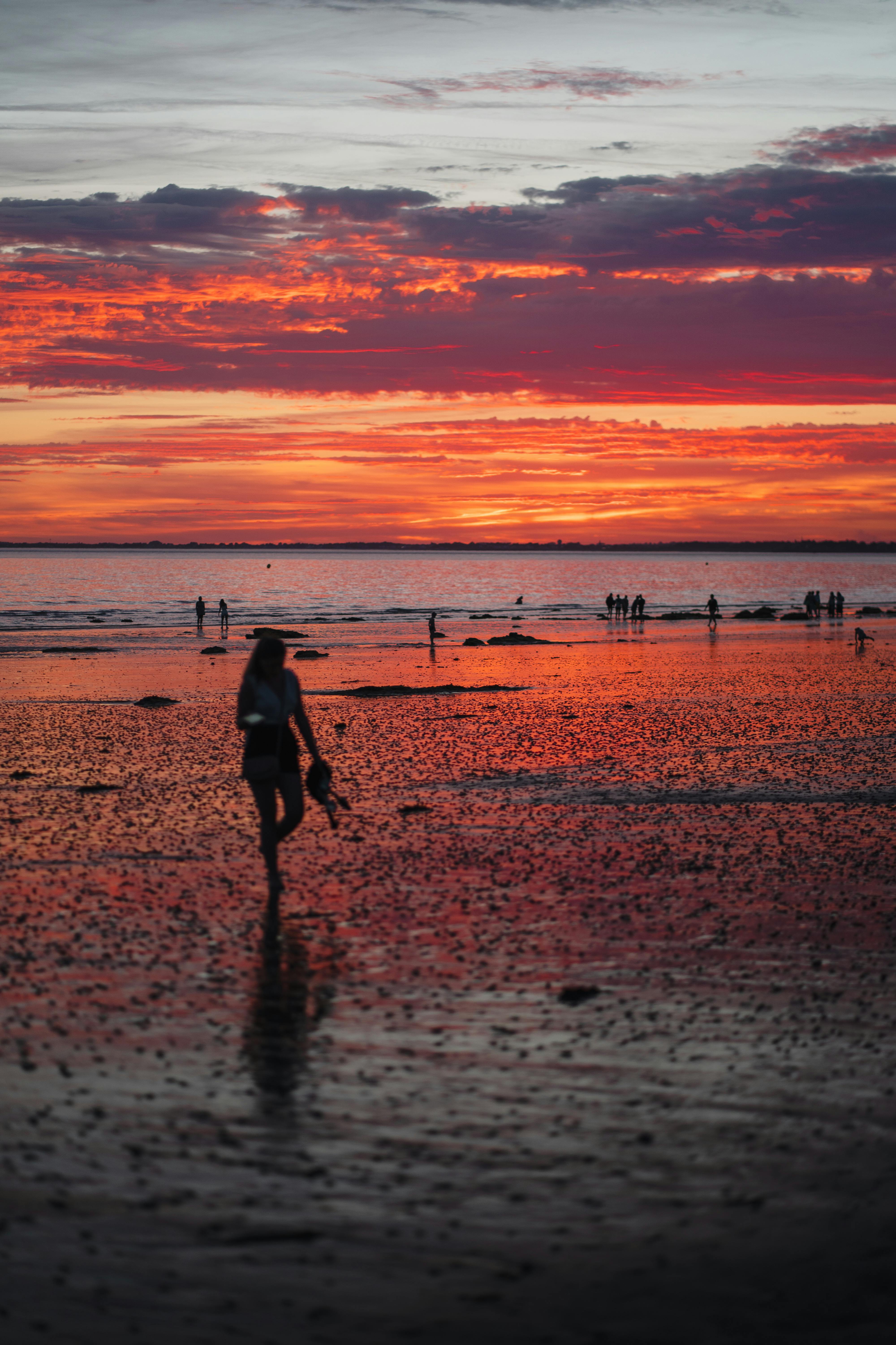 在法国布列塔尼的佩内斯廷海滩，夕阳的余晖映照在一名女子的剪影上