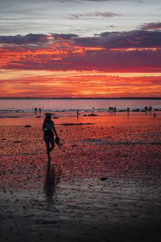 Woman silhouetted against a vivid sunset at Pénestin Beach, Bretagne, France.