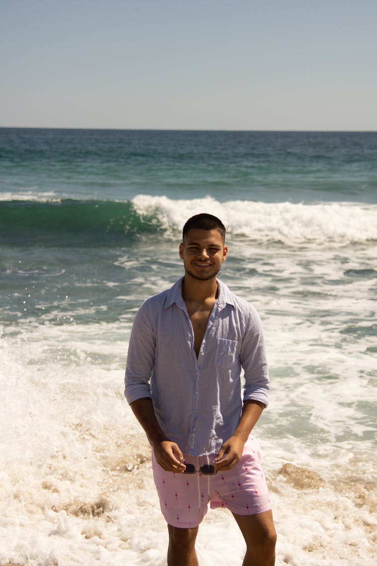 Young Man Standing On The Beach And Smiling 