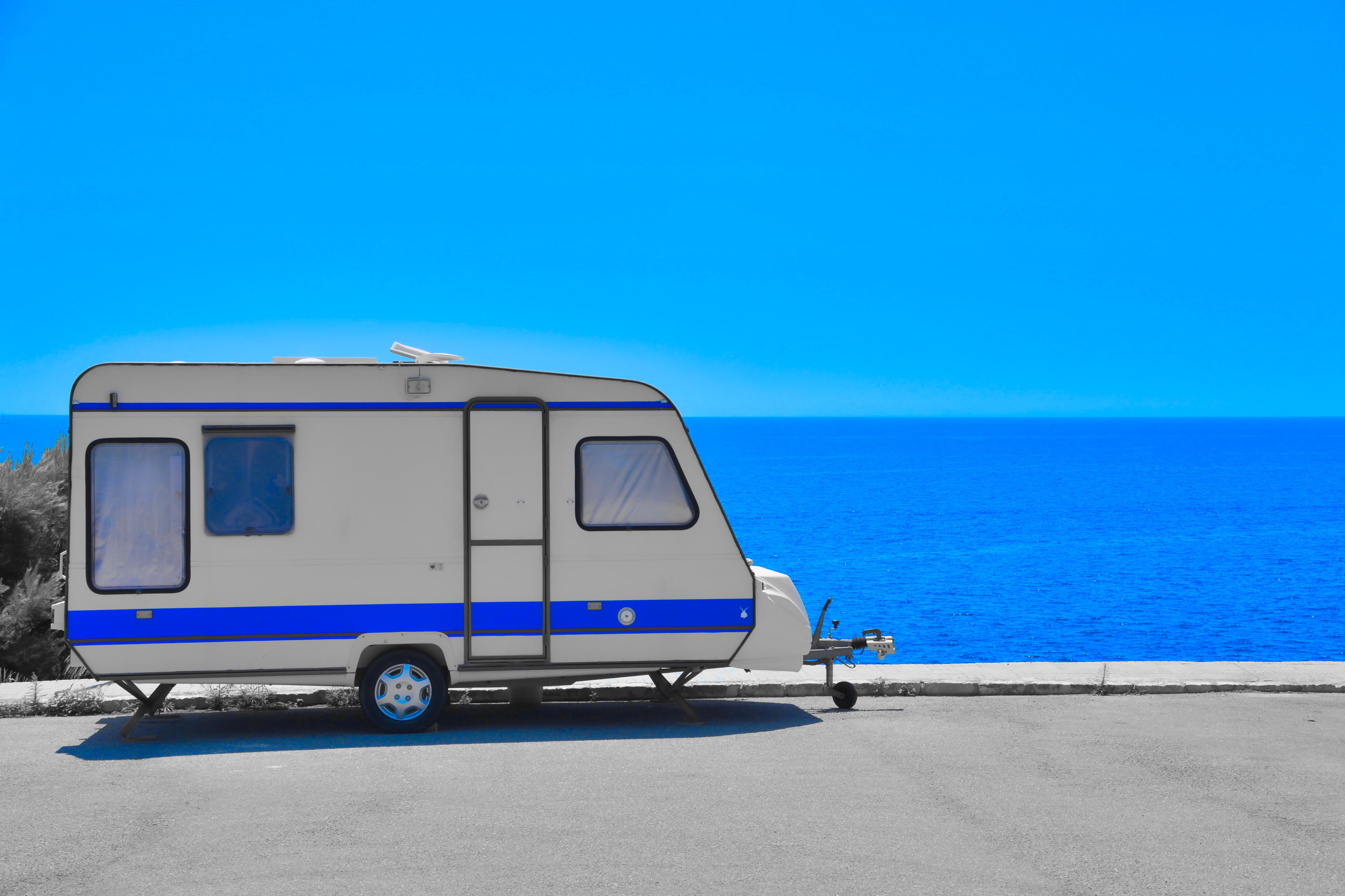 A parked camper trailer overlooks the serene sea in Porto Cristo, Spain.