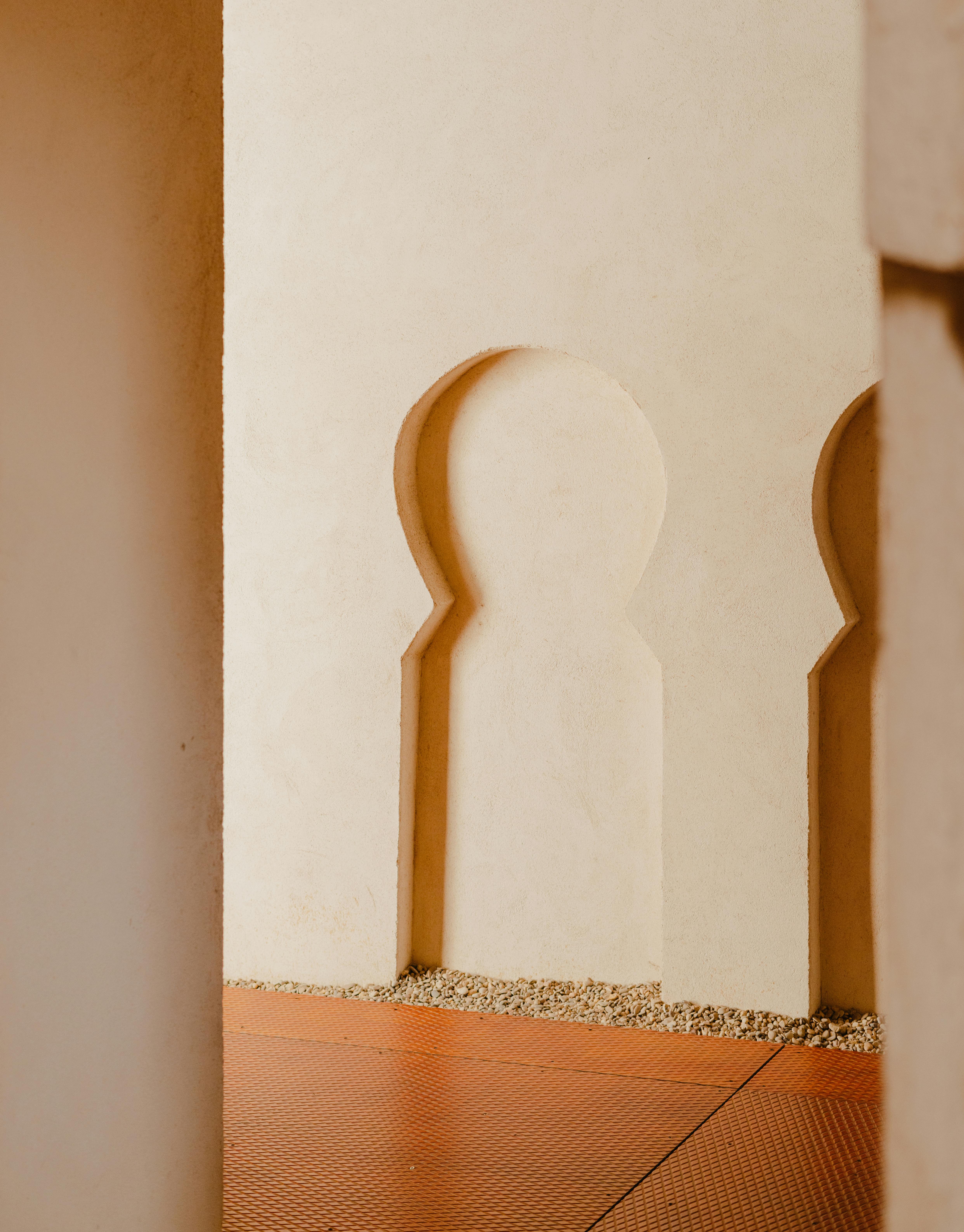 Minimalist architectural design with soft beige tones and intricate archway patterns.