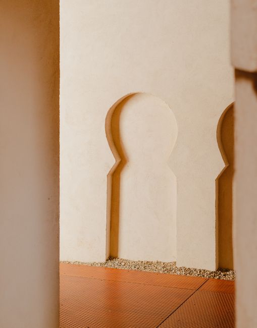 Minimalist architectural design with soft beige tones and intricate archway patterns.