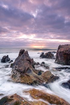 Dramatic sunset over rocky seashore in Vila Nova de Gaia, capturing vibrant and moody ocean scenery.