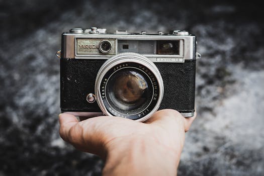 Close-up of a vintage Yashica camera held by a hand, showcasing classic design and lens detail.