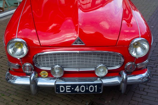 Close-up of a vintage red classic car parked on a brick city street.