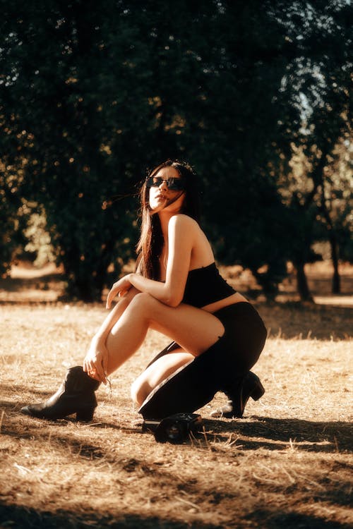 Pretty Woman with Sunglasses Crouching in Park
