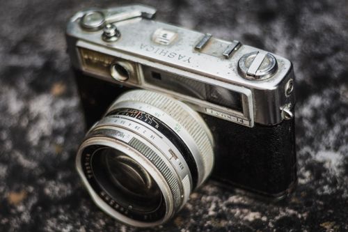 Free Vintage Yashica camera with classic lens on textured stone, showcasing retro design. Stock Photo
