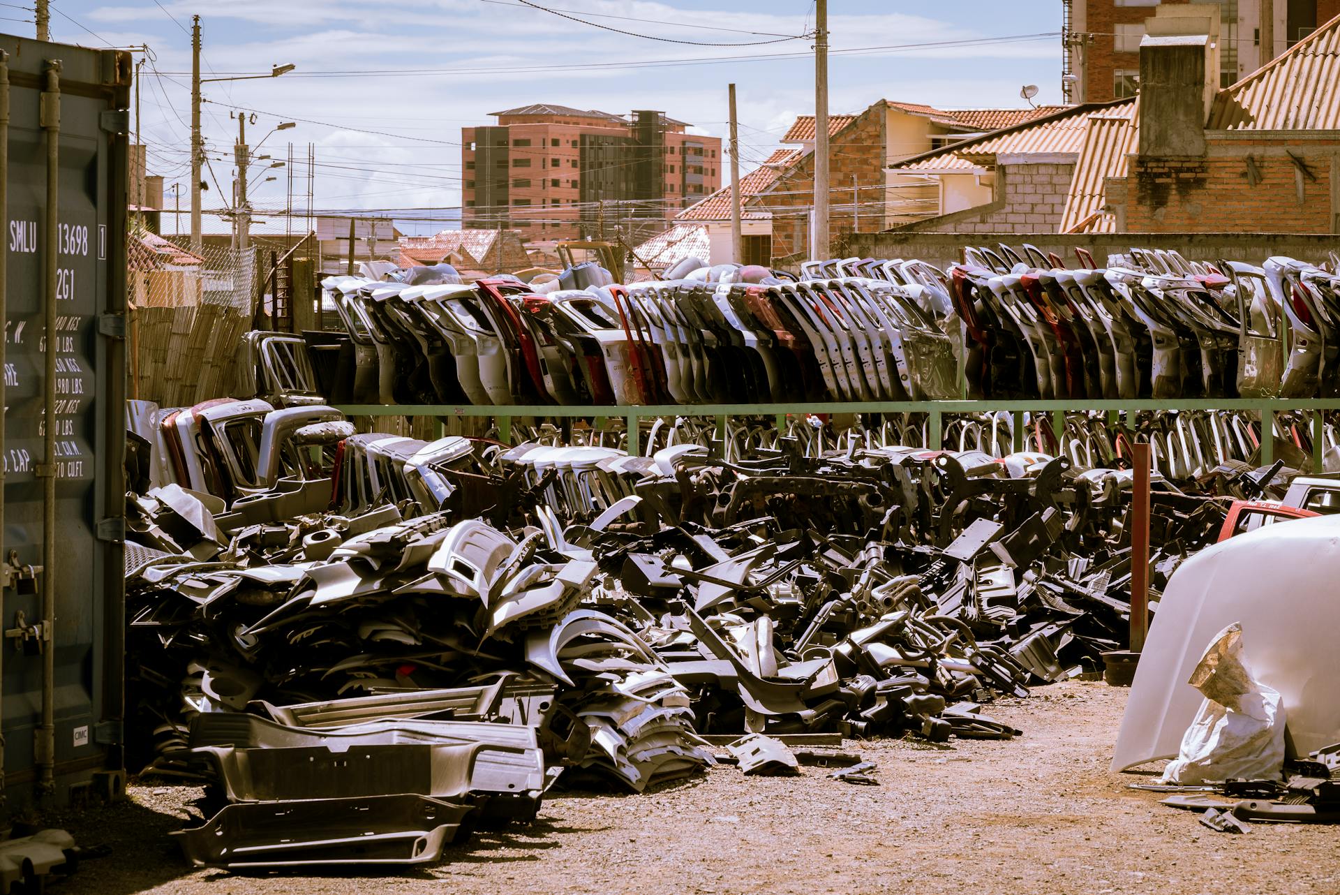 Recycled car parts stacked in a sunny junkyard in Cuenca, Ecuador.