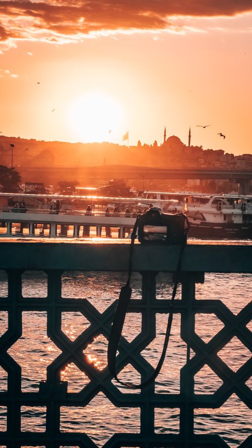 Free A breathtaking sunset view of Istanbul skyline with a camera resting on a bridge overlooking the Bosporus. Stock Photo