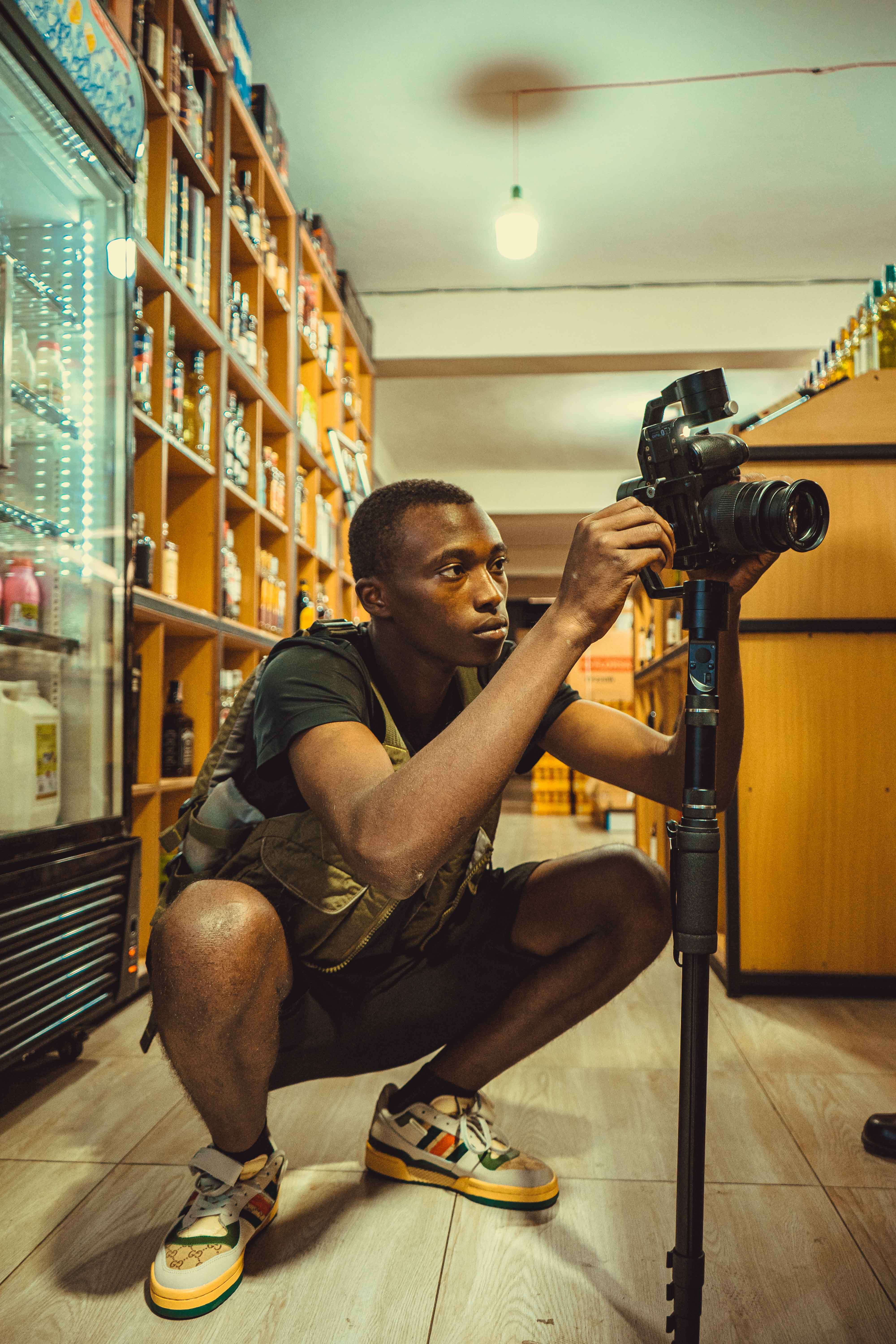 Young man setting up a camera on a tripod inside a liquor store, focused on capturing dynamic shots.