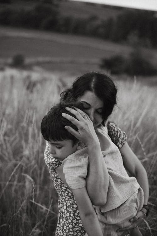 Mother Hugging Sleeping Son on Field