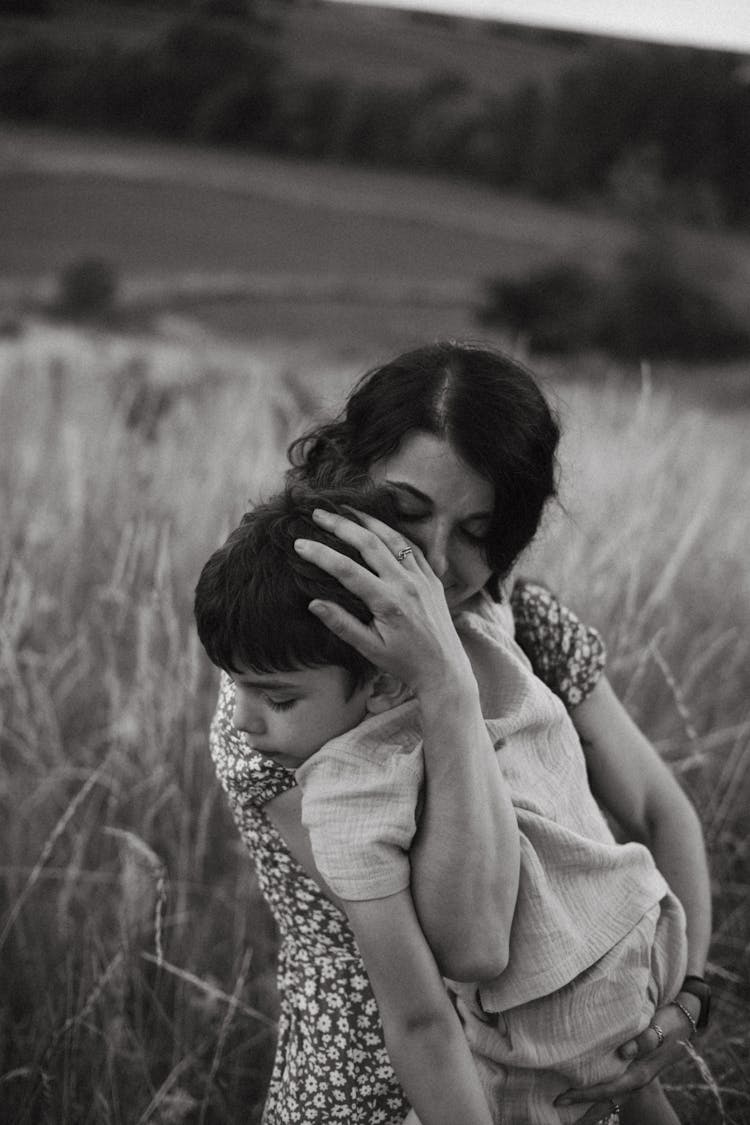 Mother Hugging Sleeping Son On Field