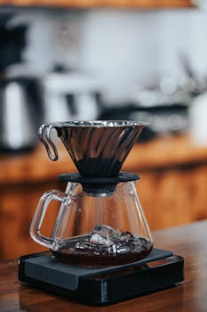 Close-up of a pour-over coffee maker with ice, capturing the essence of artisanal coffee brewing in a café setting.