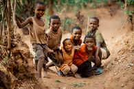 Group of smiling children posing together in a rural setting in Bujumbura, Burundi.