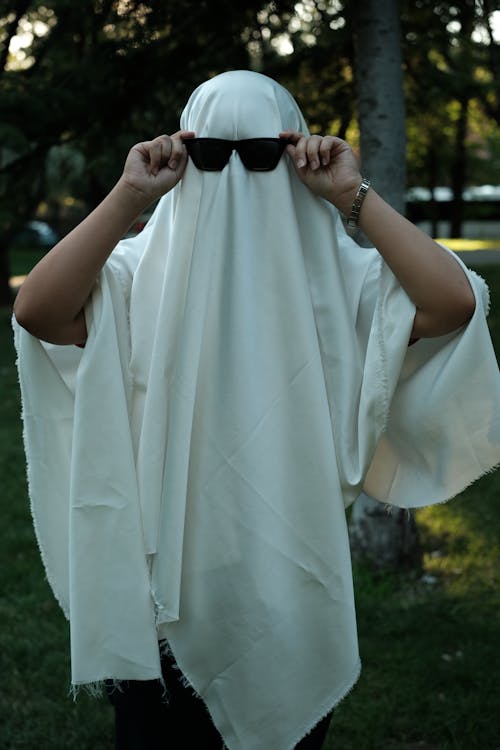 A Person Dressed as a Ghost Wearing a White Sheet and Sunglasses 