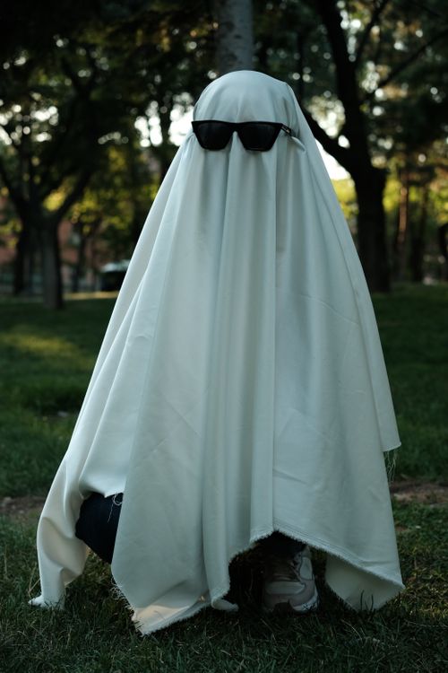 Free A playful ghost costume with sunglasses in a park setting, perfect for Halloween. Stock Photo