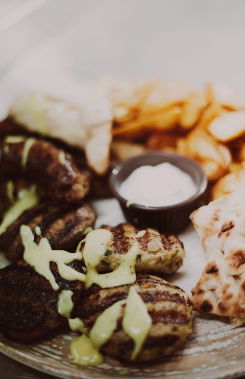Free Close-up of traditional Greek cuisine featuring souvlaki, pita, and tzatziki dip on a rustic platter. Stock Photo