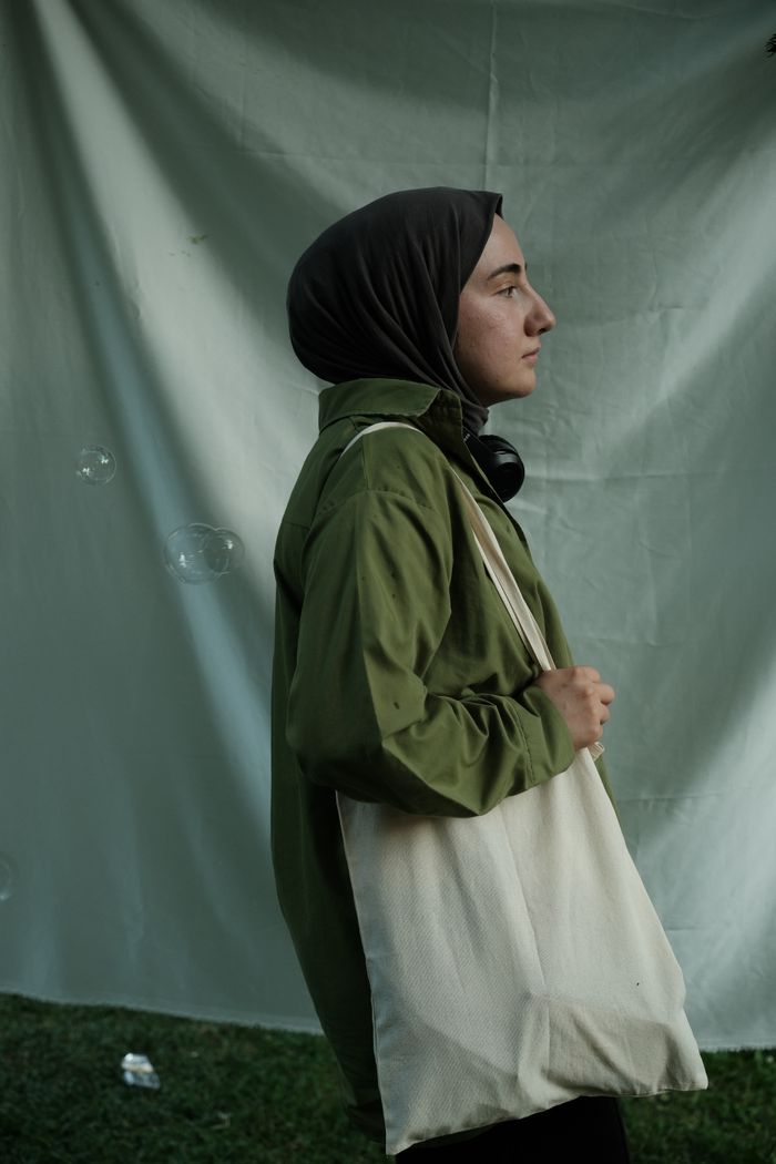 Woman carrying a plain canvas tote outdoors, by Alican Helik on Pexels