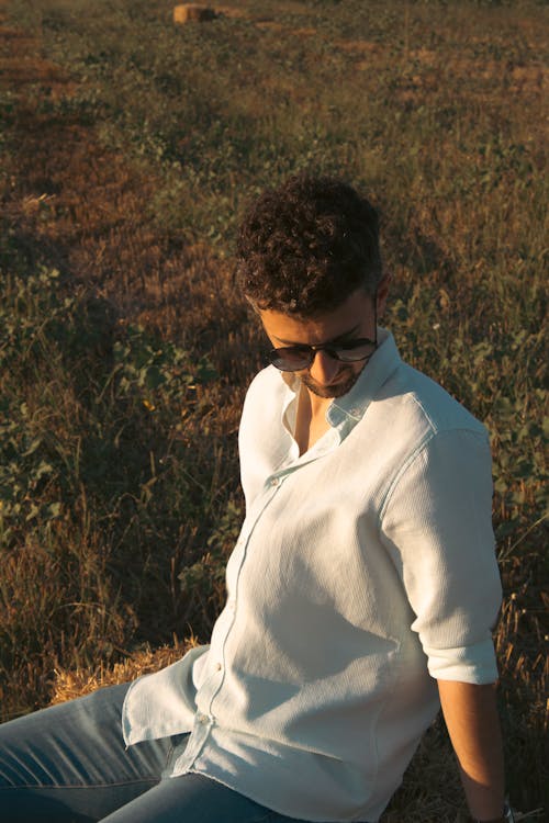 Young Man Sitting on a Meadow in Summer