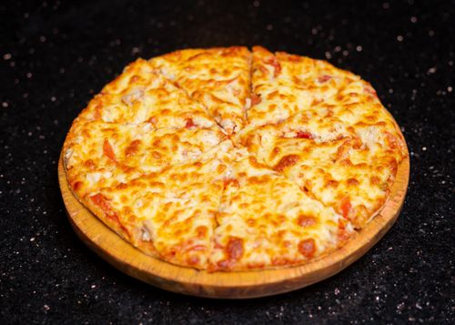 Free Freshly baked cheese pizza on a wooden platter, perfect for a cozy lunch. Stock Photo