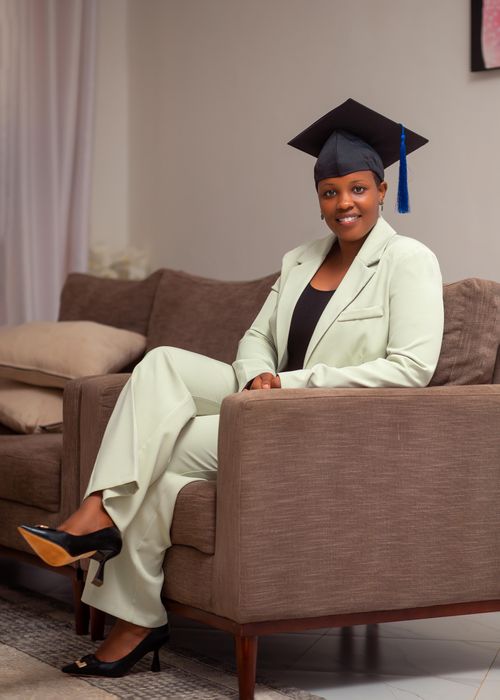 Free Elegant young woman in suit with graduation cap sitting on sofa indoors Stock Photo