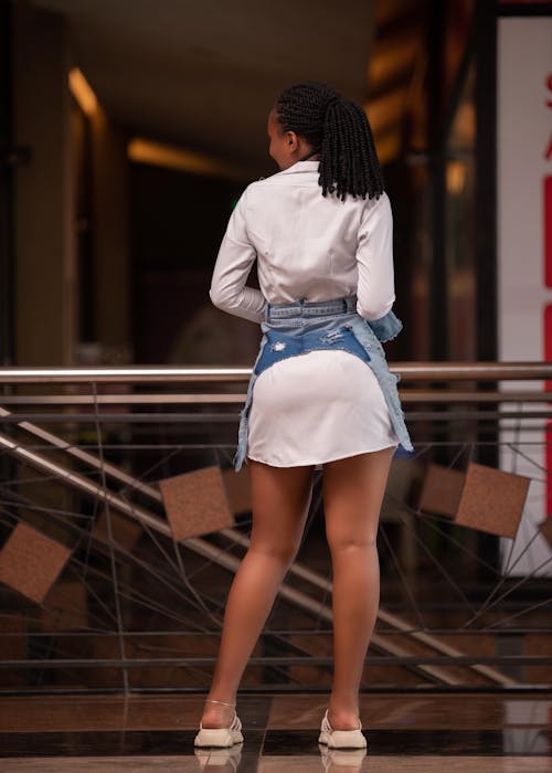 Back View of a Young Woman in a Trendy Outfit Standing in a Modern Interior 