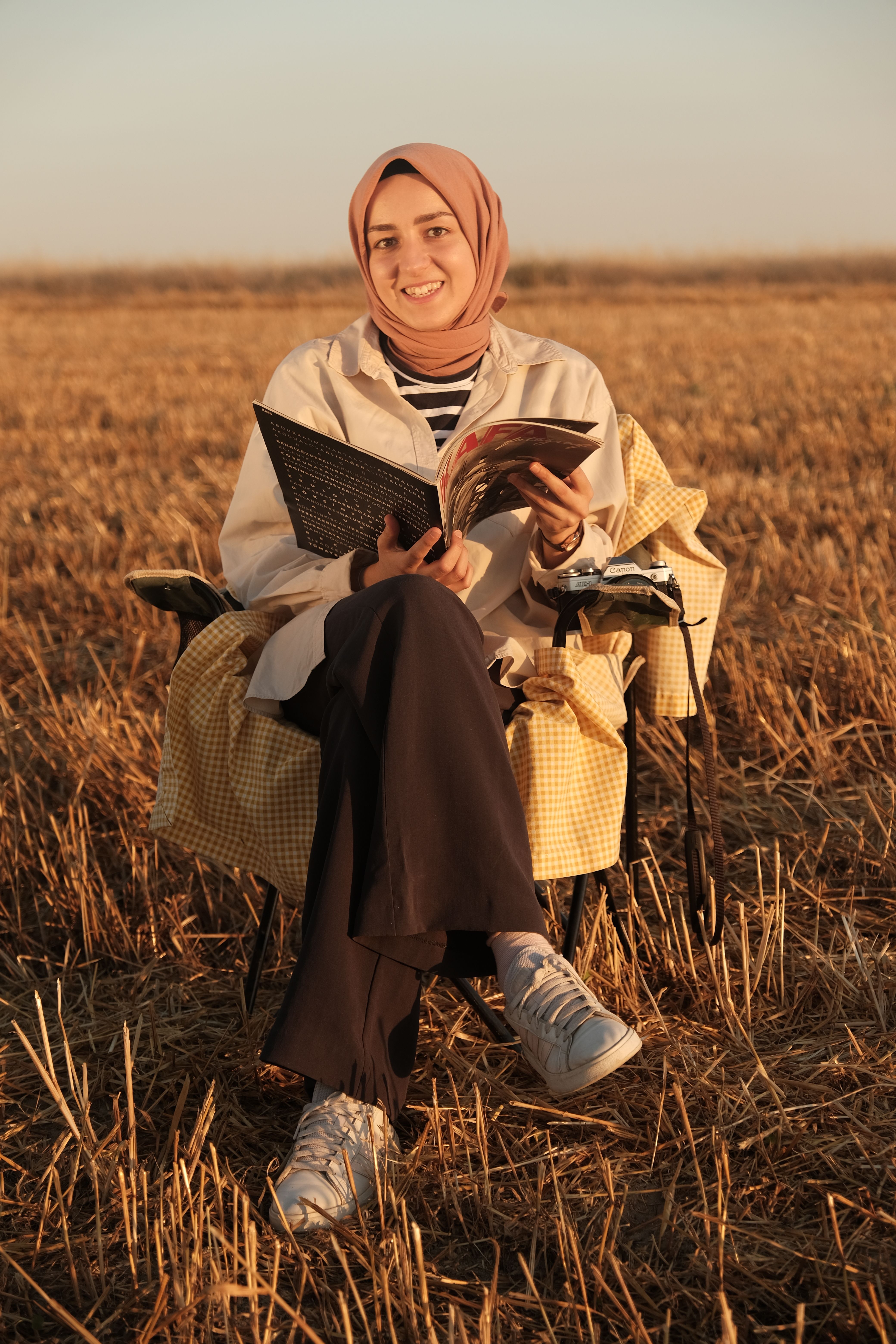 Smiling Woman in Hijab Sitting on Field at Sunset · Free Stock Photo