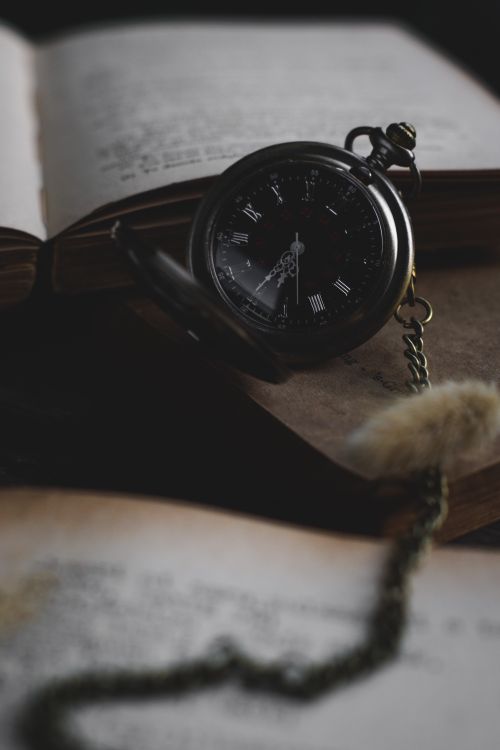 Free Close-up of a vintage pocket watch resting on an open book, evoking a nostalgic and timeless feel. Stock Photo