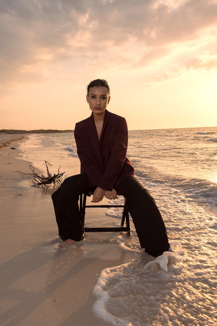 Woman Posing On Chair On Beach At Sunset