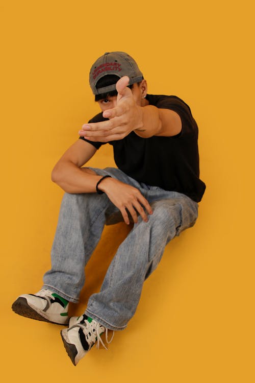 Young Man in a Casual Trendy Outfit Posing in Studio on Yellow Background 