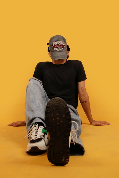 Young Man in a Casual Trendy Outfit Posing in Studio on Yellow Background 