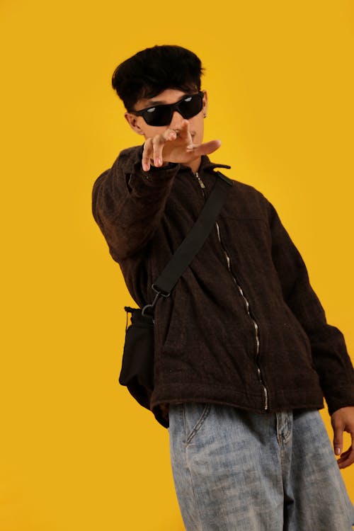 Young Man in a Casual Trendy Outfit Posing in Studio on Yellow Background 