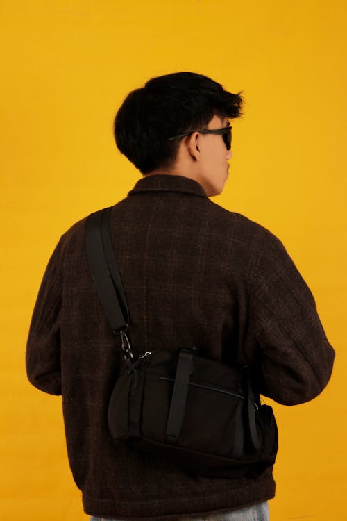 Young Man in a Casual Trendy Outfit Posing in Studio on Yellow Background 